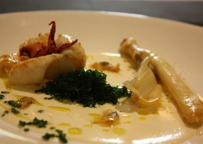 Ensalada de chipirón, navaja y coquina sobre fondo de ajoblanco y espinaca frita