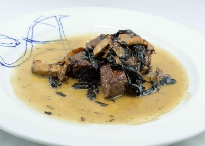 Dados de carne roja en semiguiso con setas